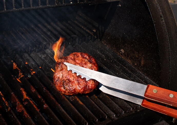 Indivíduo utilizando um pegador de churrasco