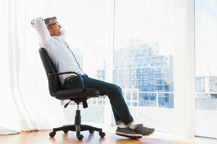 Homem sorridente sentado na cadeira do escritório e relaxando.