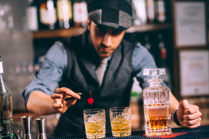 Homem preparando um coquetel de whisky com gelo