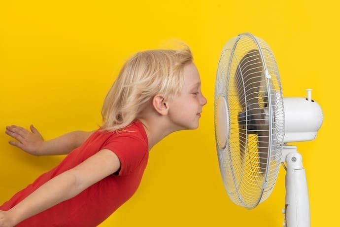 Criança e Ventilador em Fundo Amarelo