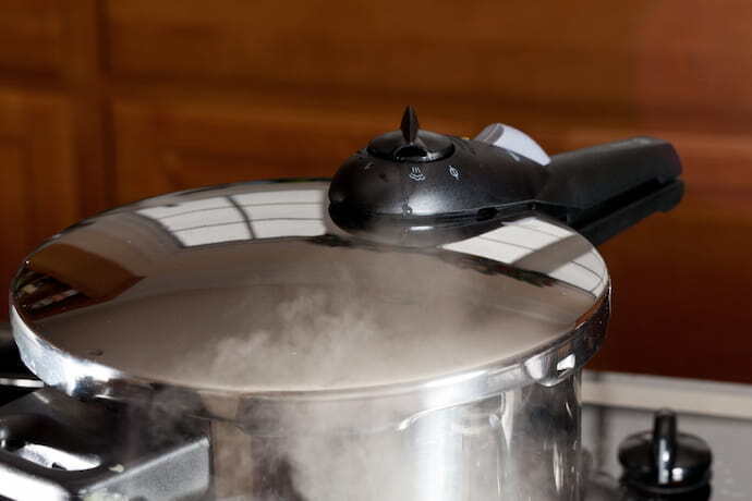 Panela de pressão de alumínio e um fundo desfocado de madeira