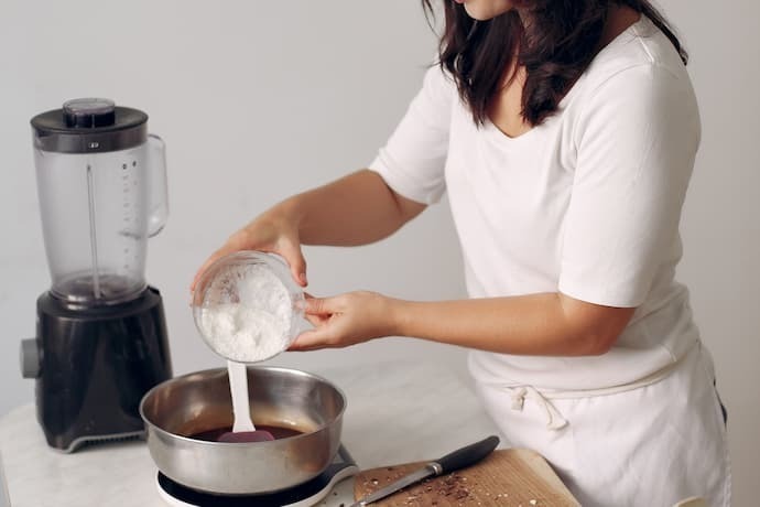 Mulher fazendo uma receita e o liquidificador ao lado