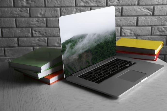 Notebook com livros na parede de tijolos