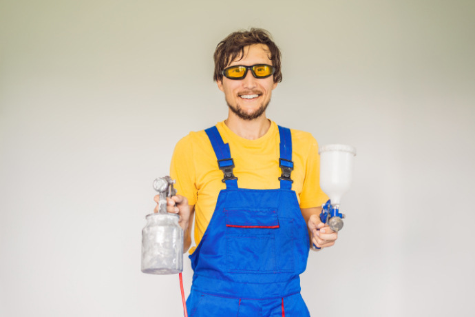 Homem segurando duas pistolas de pintura elétrica