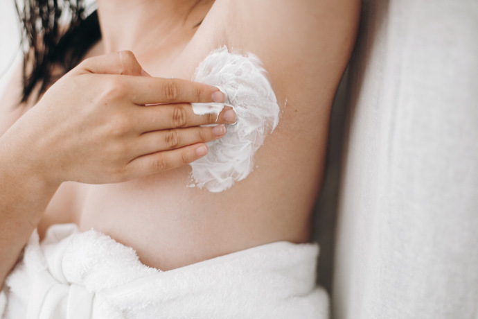 Mulher aplicando creme depilatório na axila