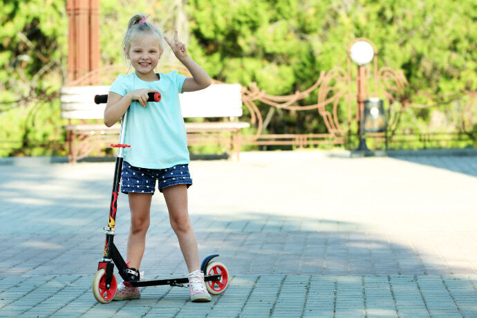 Menina sorridente com um patinete