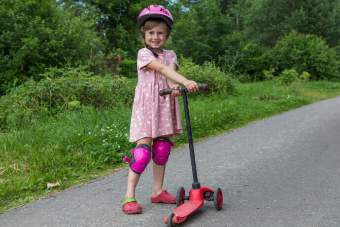 Menina com equipamento de proteção e um patinete