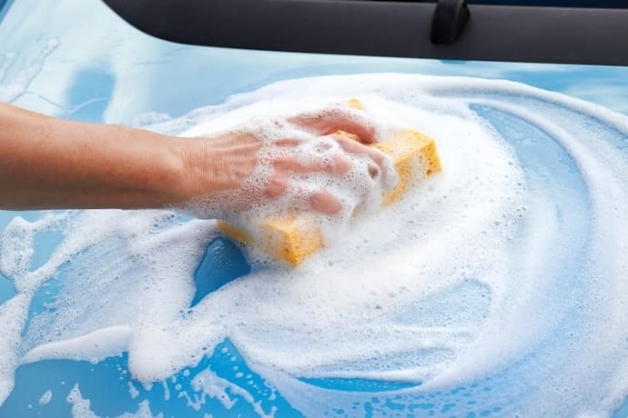 Alguém passando uma esponja com espuma no carro