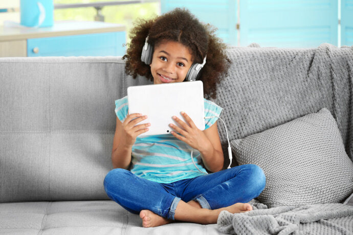 Menina sentada no sofá usando um tablet