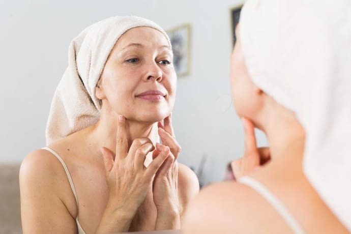 Mulher madura aplicando creme para o rosto