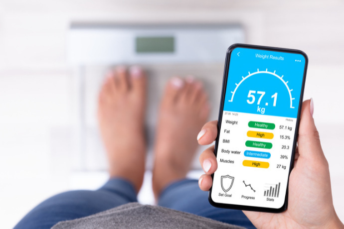 Indivíduo verificando pelo celular o dados mensurados pela balança