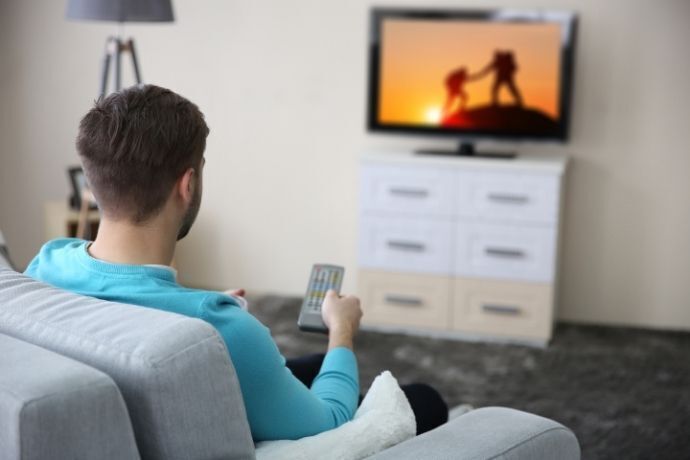 Homem no sofá assistindo TV