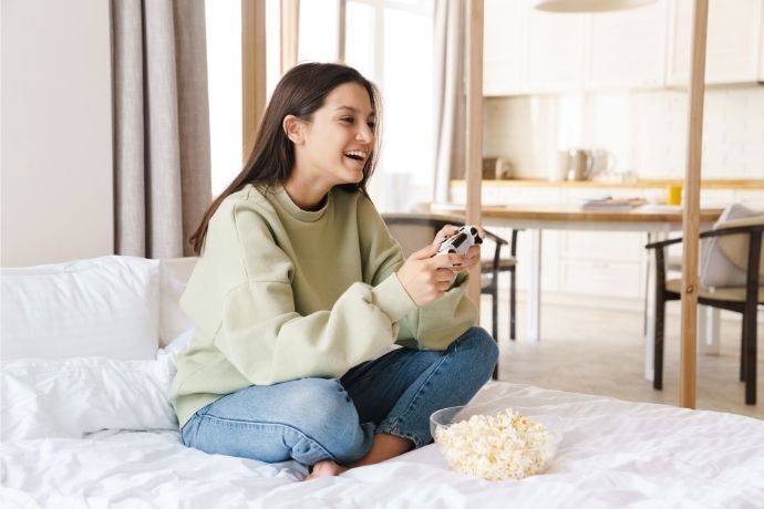 Mulher sentada na cama jogando video games