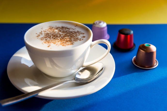 Xícara com café cremoso e cápsulas do tipo latte