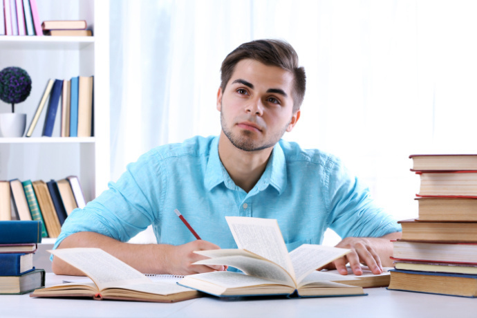 Homem lendo alguns livros sobre a mesa