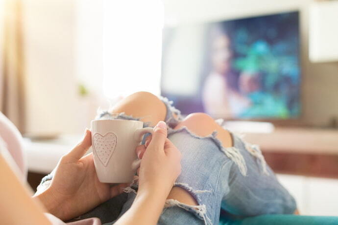 Jovem relaxando no sofá em casa, assistindo tv