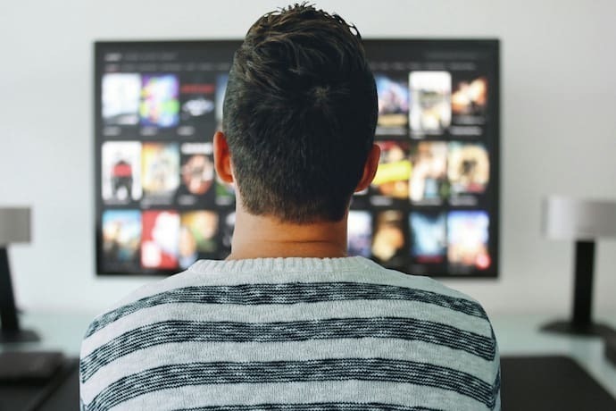 Homem e mulher no sofá assistindo TV em vasos de flores