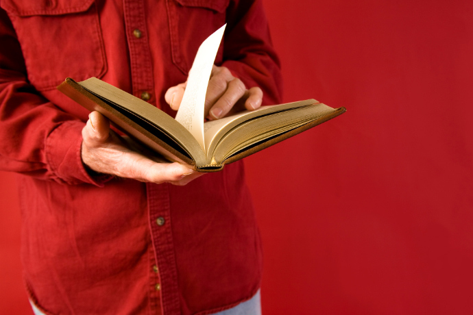 Indivíduo folheando o livro em um fundo vermelho