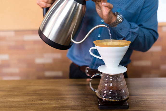 Homem colando água no coador de café