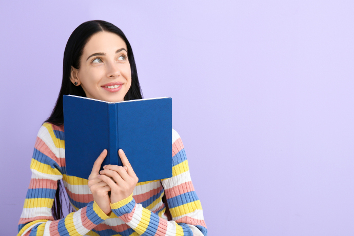 Mulher segurando um livro em um fundo lilás