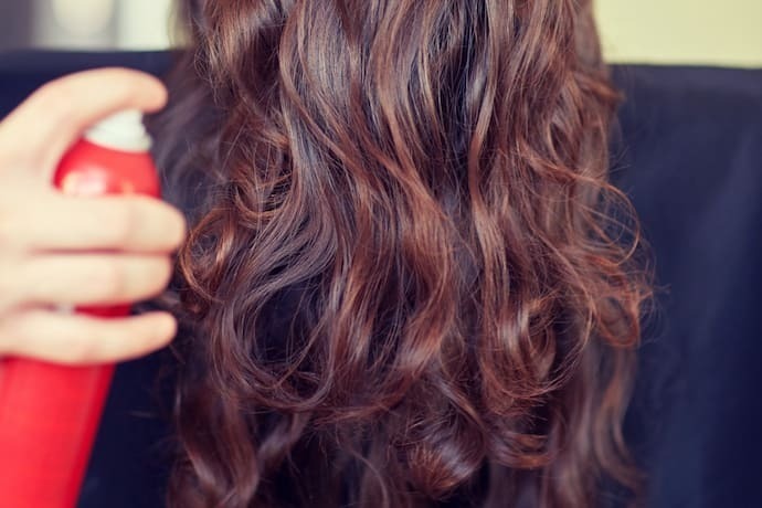 Mulher segurando um fixador de cabelo e cabelo