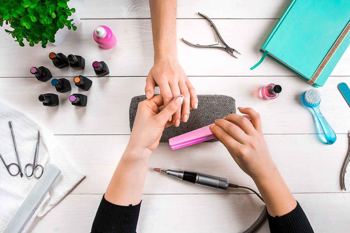 Manicure lixando as unhas de uma mulher