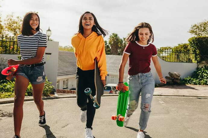 Três meninas sorridentes segurando skates nas mãos