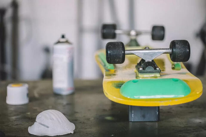 Skate amarelo, de ponta cabeça, com foco nas rodas e detalhe verde